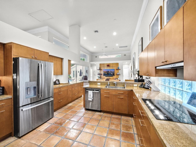 kitchen with under cabinet range hood, a peninsula, a sink, appliances with stainless steel finishes, and brown cabinets