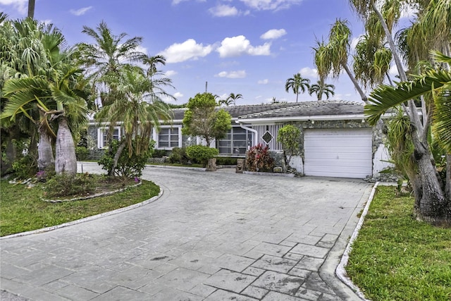 single story home with an attached garage, decorative driveway, and a tiled roof