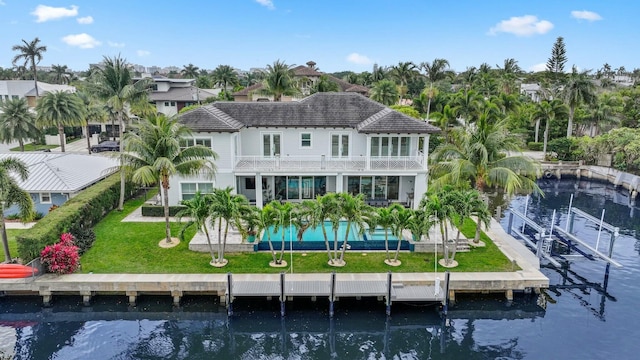 back of property featuring a water view, a balcony, and a lawn