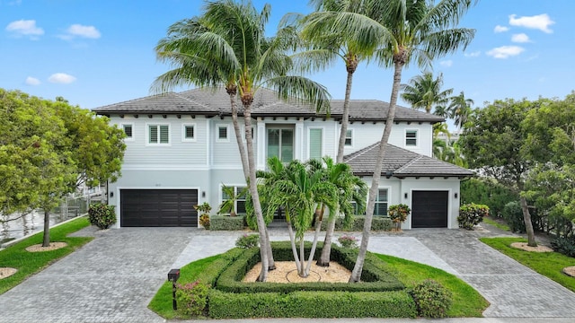 view of front of property with a tiled roof, decorative driveway, fence, and stucco siding