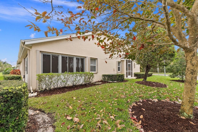 back of house with a lawn and stucco siding