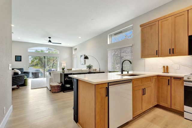 kitchen featuring appliances with stainless steel finishes, open floor plan, a peninsula, light countertops, and a sink