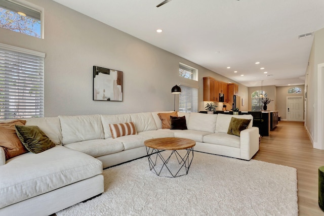 living room featuring light wood-style floors, visible vents, and recessed lighting