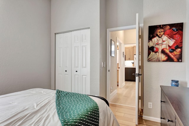 bedroom with a closet, light wood-style flooring, and baseboards