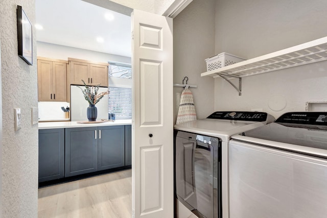 washroom featuring light wood-style floors, laundry area, and washer and clothes dryer