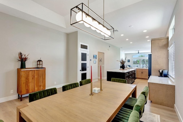 dining space featuring baseboards, light wood finished floors, and recessed lighting