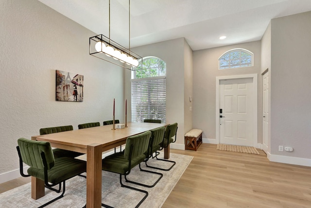 dining space with light wood-type flooring, baseboards, and a textured wall