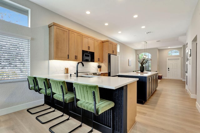 kitchen featuring a kitchen island, pendant lighting, light countertops, and freestanding refrigerator