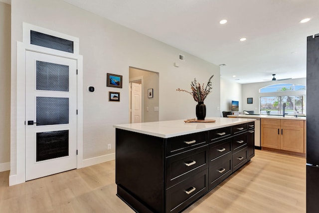 kitchen featuring light countertops, open floor plan, light brown cabinets, a kitchen island, and light wood-type flooring