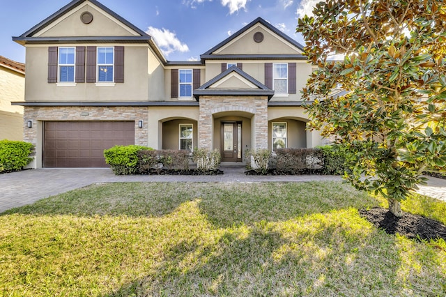 view of front of home featuring stone siding, a front lawn, decorative driveway, and stucco siding