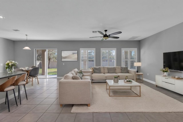 living room featuring a ceiling fan, visible vents, baseboards, and light tile patterned floors