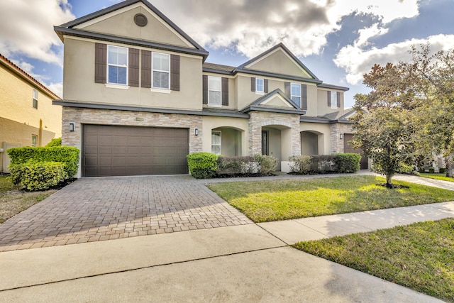 view of front of house with stone siding, decorative driveway, and stucco siding