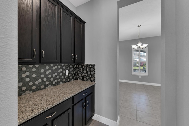 kitchen featuring tasteful backsplash, light tile patterned floors, baseboards, and light stone countertops