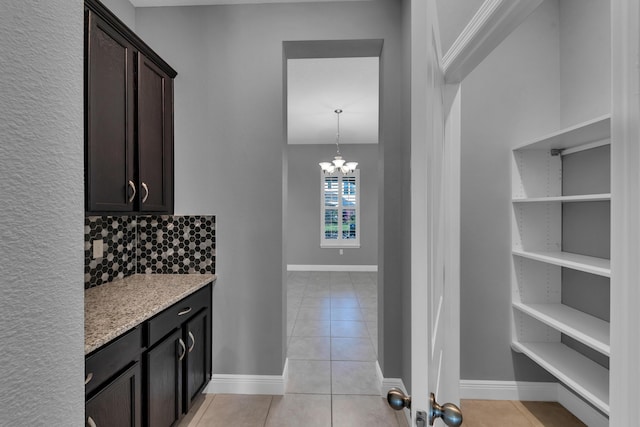 kitchen featuring pendant lighting, backsplash, dark brown cabinets, and light tile patterned floors