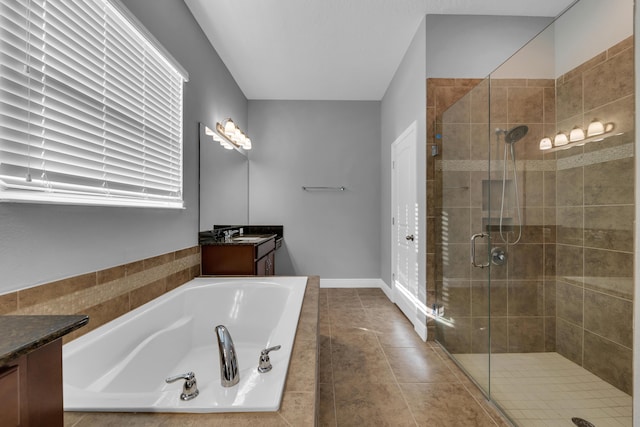 bathroom with tile patterned flooring, a garden tub, vanity, baseboards, and a stall shower