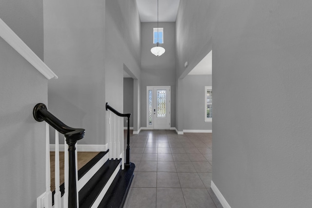 entrance foyer with baseboards, light tile patterned flooring, stairs, and a healthy amount of sunlight