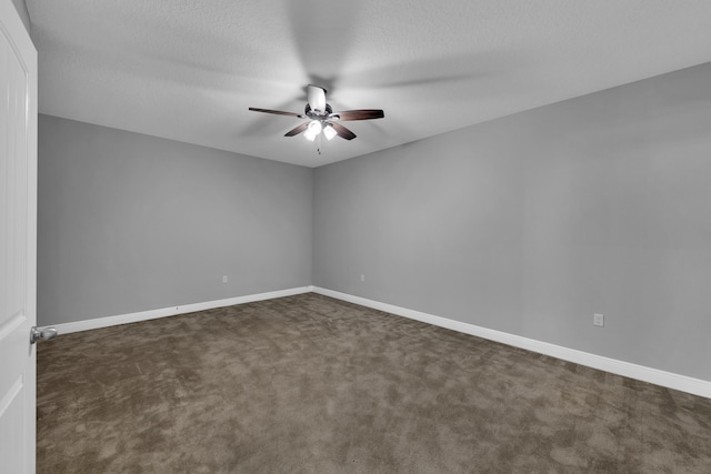 spare room with a textured ceiling, baseboards, dark colored carpet, and a ceiling fan