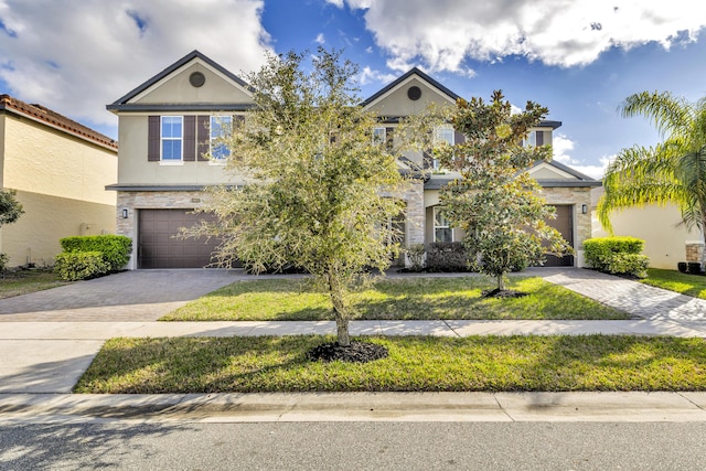 view of front of property with a garage, stone siding, decorative driveway, and stucco siding