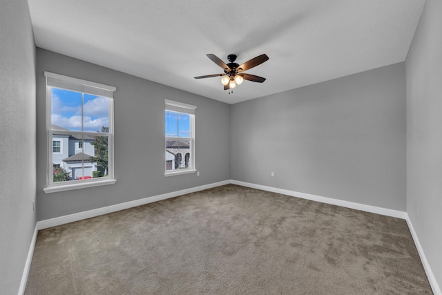 spare room featuring carpet, ceiling fan, and baseboards