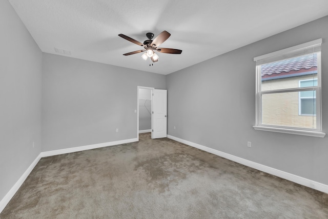 unfurnished room featuring carpet floors, visible vents, baseboards, and a ceiling fan