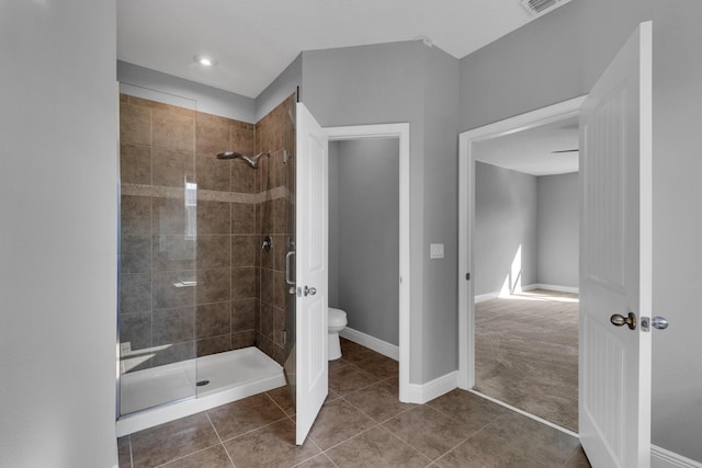 bathroom featuring toilet, tile patterned flooring, baseboards, and walk in shower