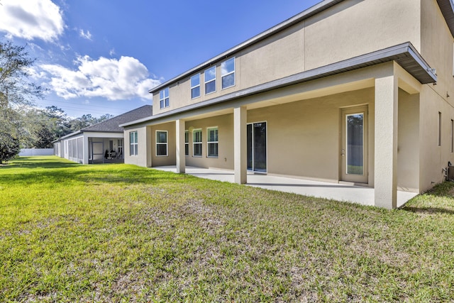 back of house with a yard, a patio, and stucco siding