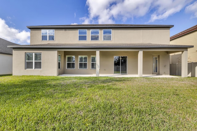 rear view of property with a yard, a patio area, fence, and stucco siding