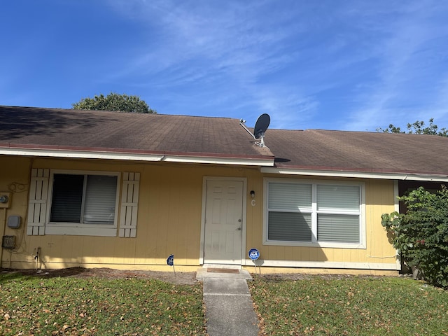 view of front facade with roof with shingles and a front yard