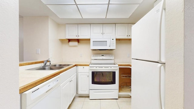 kitchen featuring white appliances, light tile patterned floors, white cabinets, and a sink