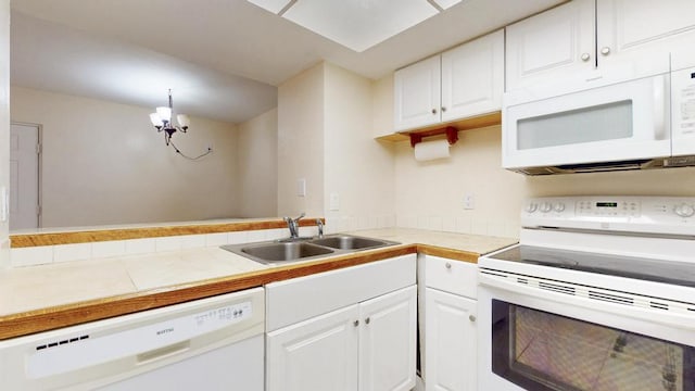 kitchen with tile countertops, white appliances, a sink, and white cabinets