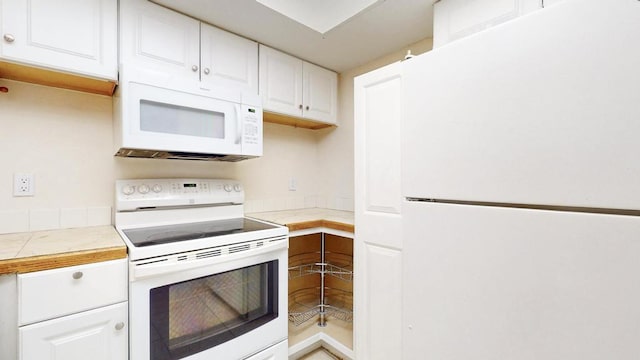 kitchen with tile counters, white appliances, and white cabinetry