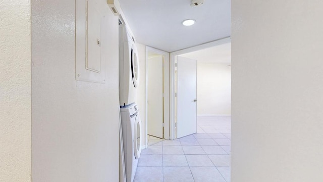 hallway with light tile patterned floors and stacked washer and clothes dryer