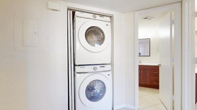 laundry area with light tile patterned floors, laundry area, stacked washer / dryer, visible vents, and electric panel