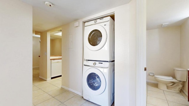 laundry area featuring laundry area, light tile patterned floors, baseboards, and stacked washer / dryer