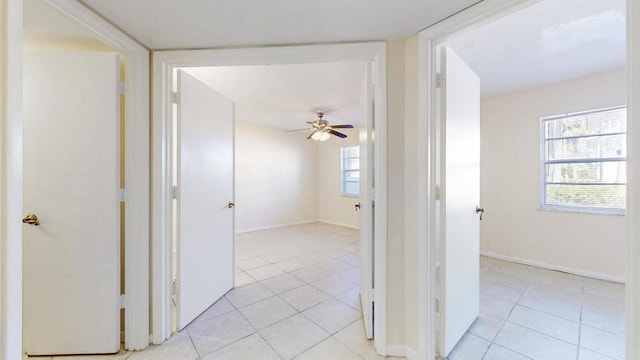 hallway featuring baseboards and light tile patterned flooring