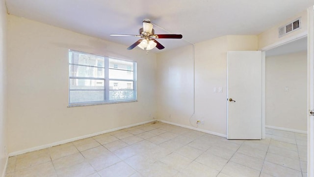 empty room featuring light tile patterned floors, a ceiling fan, visible vents, and baseboards