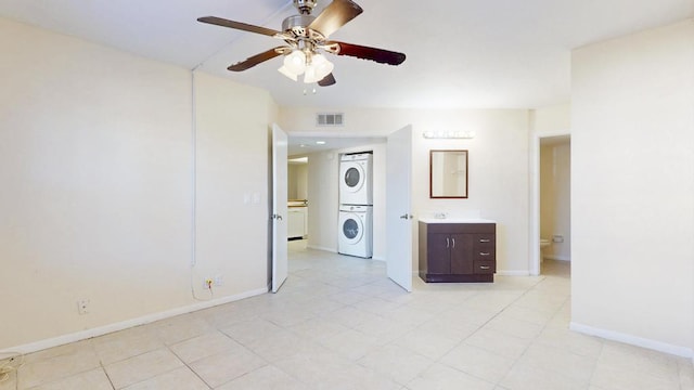 interior space featuring baseboards, visible vents, ceiling fan, and stacked washing maching and dryer