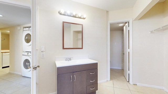 bathroom with stacked washer and clothes dryer, vanity, baseboards, and tile patterned floors