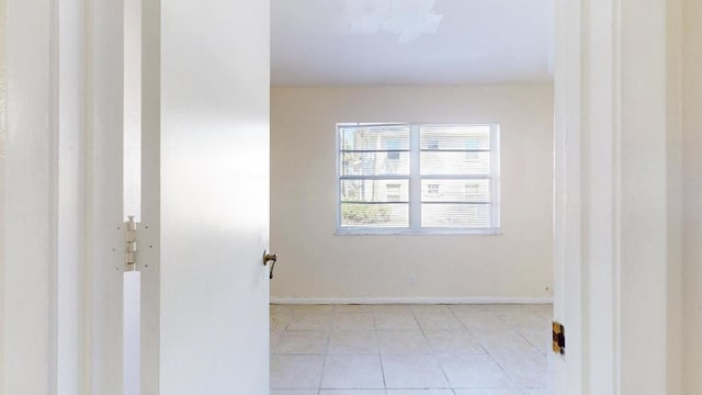 empty room featuring baseboards and light tile patterned floors