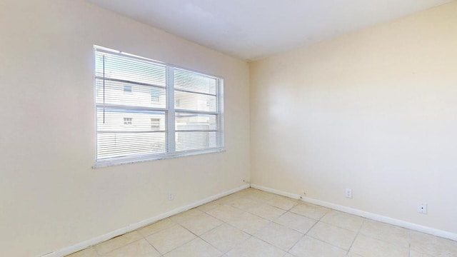 unfurnished room with light tile patterned flooring and baseboards