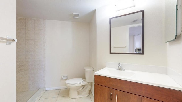 full bathroom featuring a tile shower, vanity, tile patterned flooring, and toilet