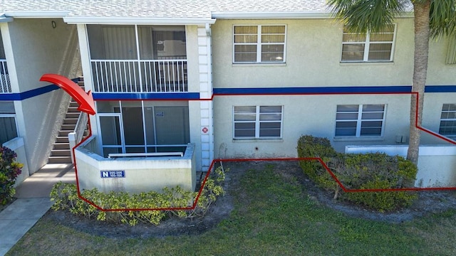 exterior space with stucco siding, stairs, and roof with shingles