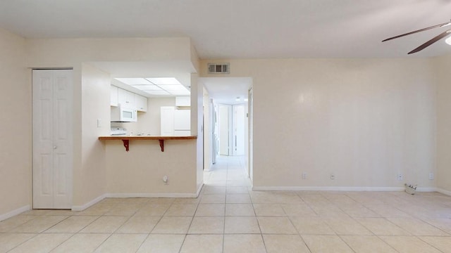 unfurnished room with light tile patterned floors, baseboards, visible vents, and a ceiling fan