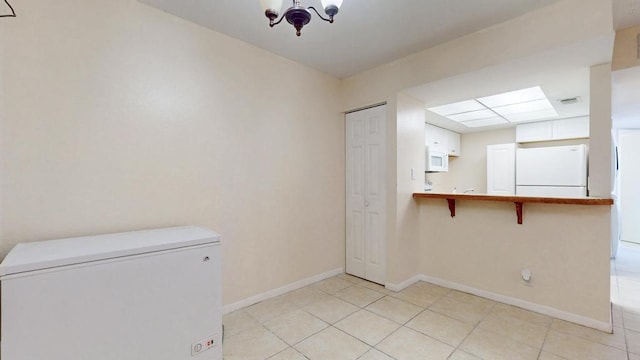 unfurnished room featuring light tile patterned floors, visible vents, baseboards, and an inviting chandelier