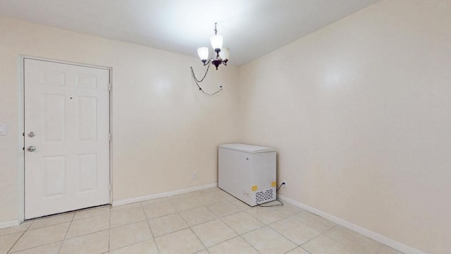 interior space featuring a chandelier, light tile patterned floors, and baseboards