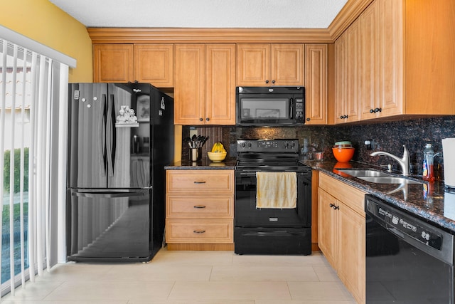 kitchen featuring tasteful backsplash, dark stone countertops, a sink, and black appliances