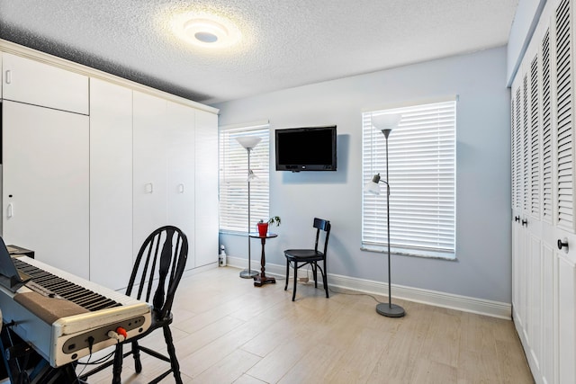 home office with light wood-style flooring, baseboards, and a textured ceiling