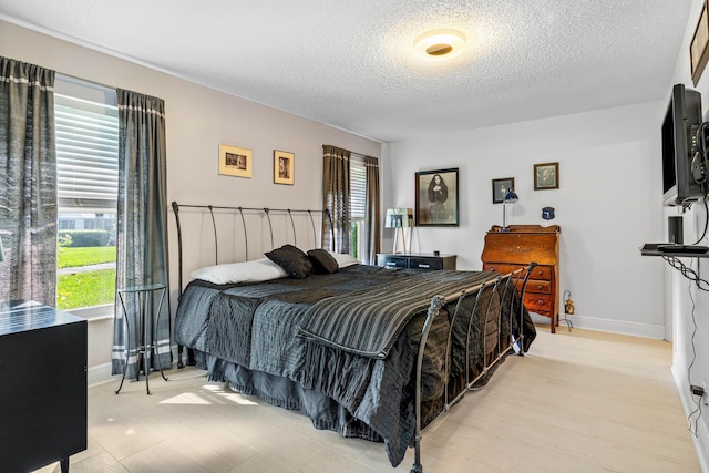 bedroom featuring a textured ceiling, multiple windows, and baseboards