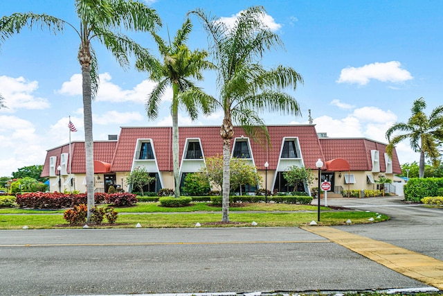 view of front of home featuring a front yard, mansard roof, and a tiled roof