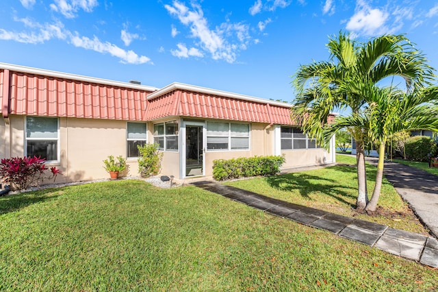 view of front of property with a tiled roof, a front lawn, and stucco siding